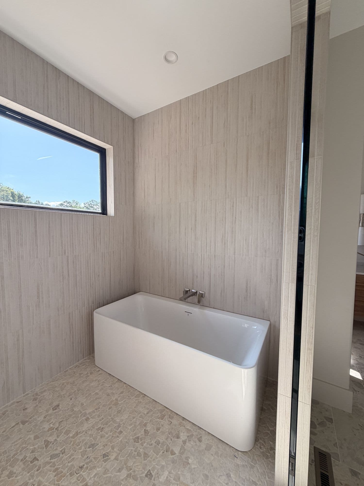Freestanding tub beneath a picture window