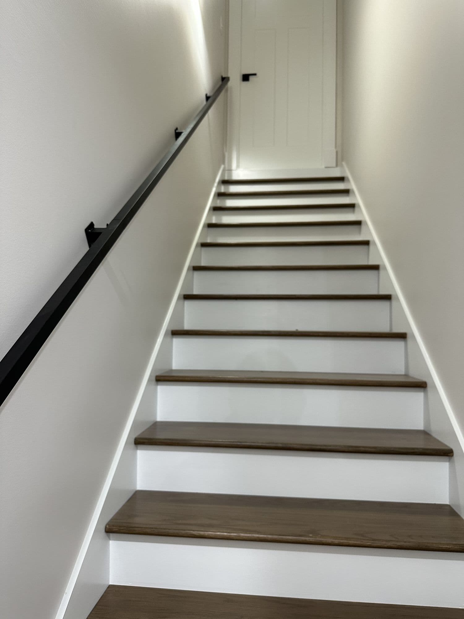 Staircase with wood treads and a black handrail