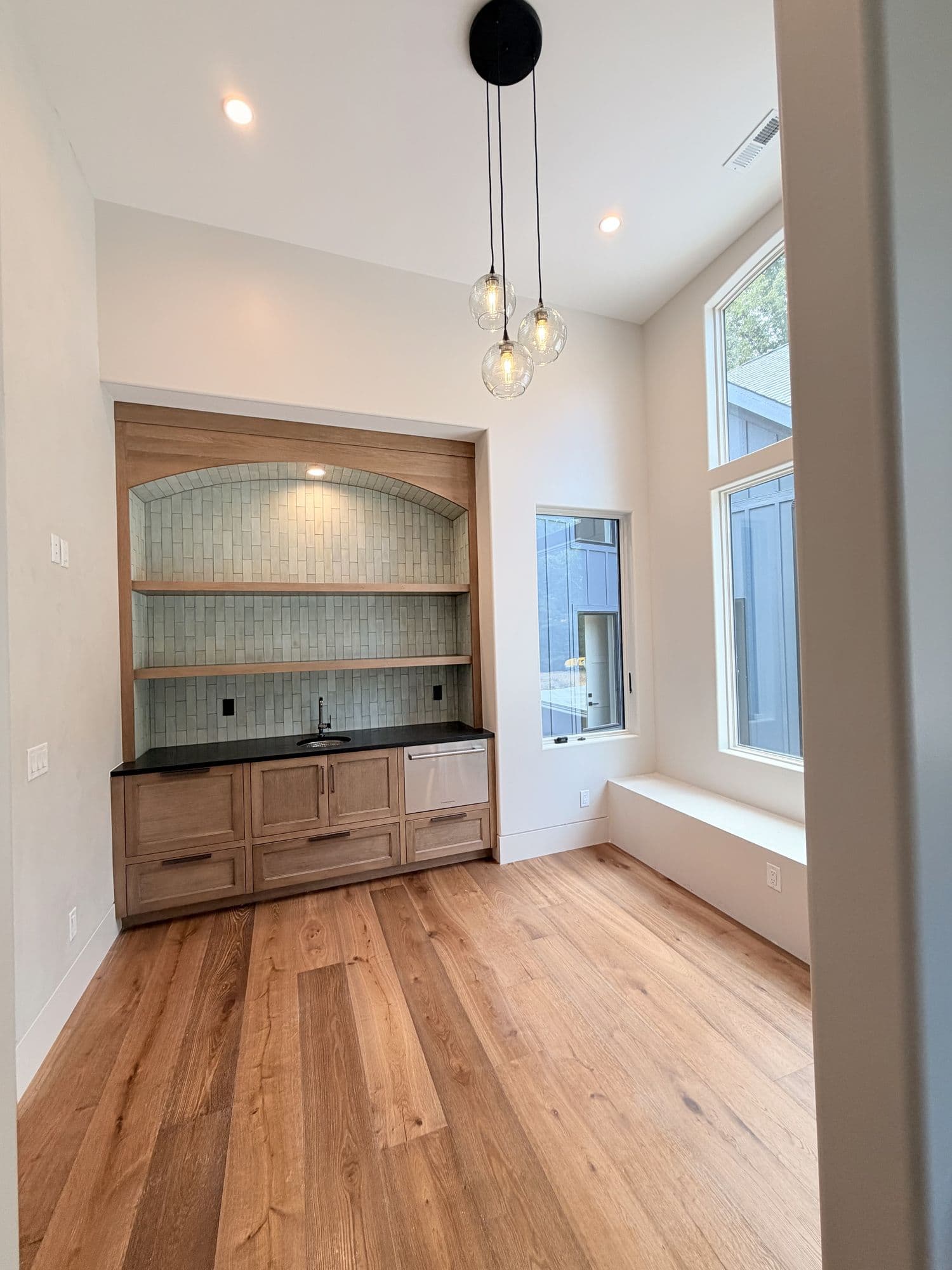 Wet bar with glass-tile backsplash and pendant lights