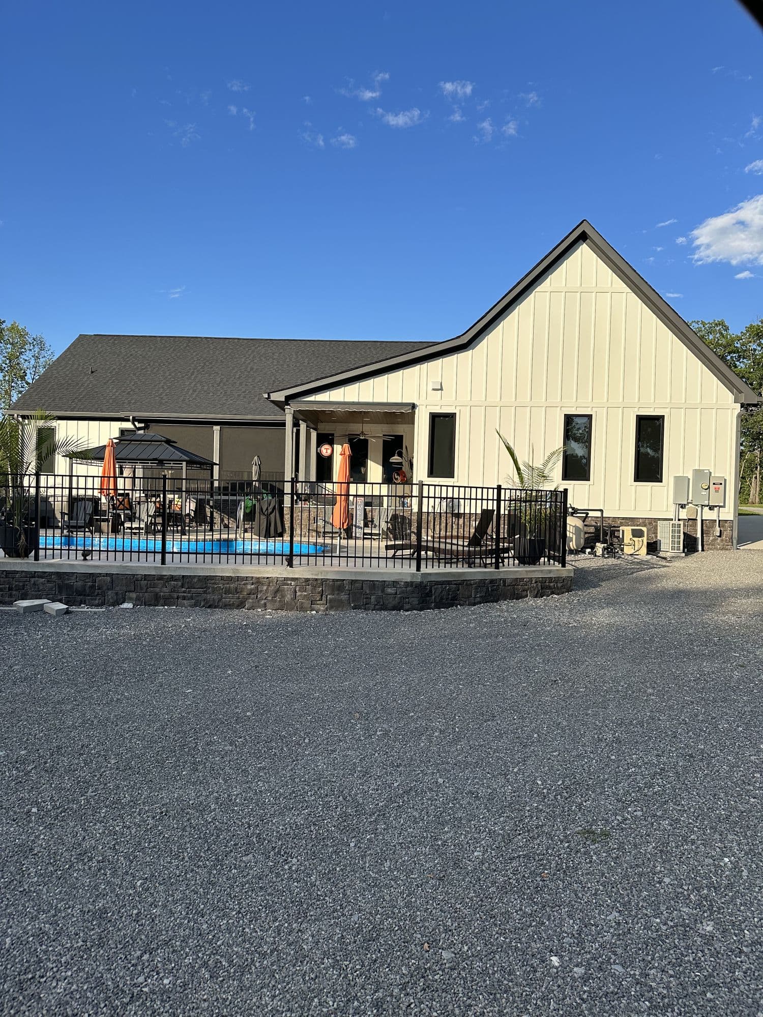 Farmhouse exterior with pool and gravel drive